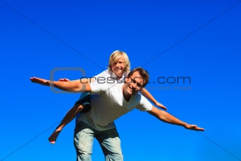 Young boy on father's back playing airplane
