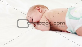 Baby sleeping in bed with his finger in his mouth