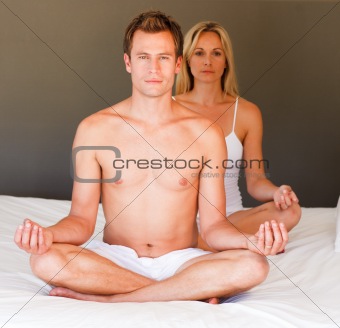 Couple doing meditating on bed