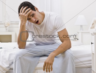 Attractive Man Sitting on His Bed Yawning