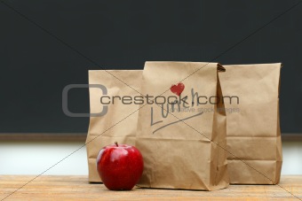 Lunch bags with  apple on school desk