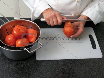 Chef is peeling bolied tomatos
