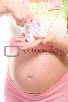belly of pregnant woman with baby socks on hands