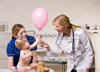 Doctor handing baby girl balloon