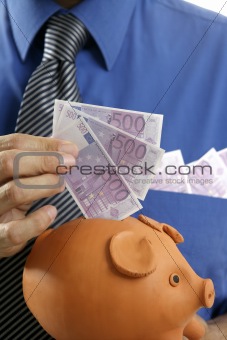 businessman insert euro notes in piggy bank