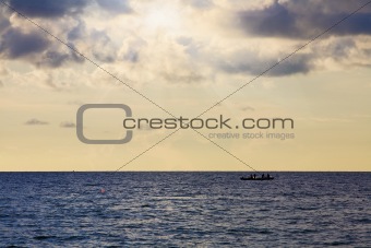 Sunset over the ocean with a fisherboat on the horizon