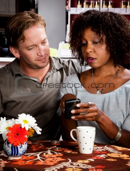 Mixed race couple in coffee house with cell phone