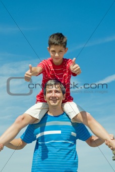child in a red shirt sitting on his father