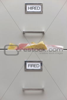 Detail of a full filing cabinet labeled hired and fired.