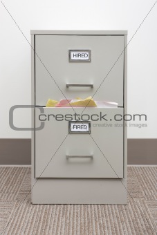 Detail of a full filing cabinet labled hired and fired.
