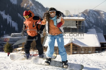 A lifestyle image of two young adult  snowboarders