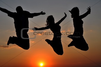 Contours of three happy people jumping at sunset