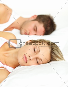 Young couple sleeping in bed with focus on woman