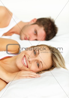 Couple resting in bed and woman smiling at the camera
