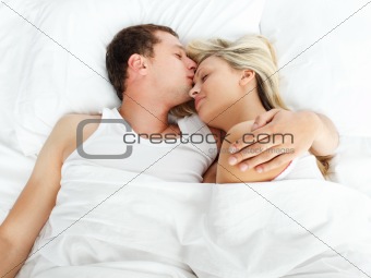 Boyfriend kissing her girlfriend in bed