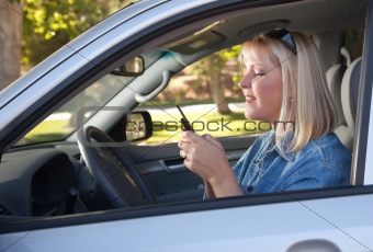 Attractive Blonde Woman Text Messaging on Her Cell Phone While Driving.