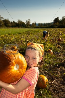 young girl with large pumpkin, in field
