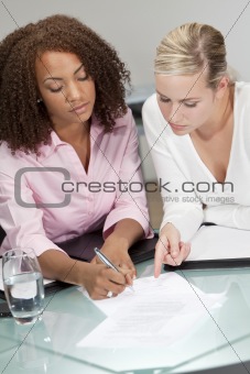 Mixed Race Young Businesswomen or Lawyers Signing A Contract