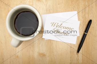 Welcome Home Note Card, Pen and Coffee Cup on Wood Background.