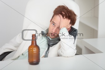 Young drunken man at office with a beer bottle