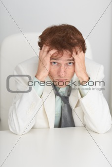 Sad young businessman sits at a table