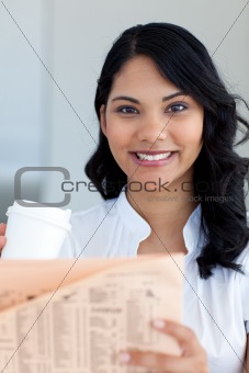 Businesswoman drinking coffee and reading a newspaper