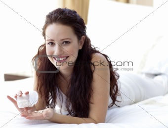 Smiling woman in bed taking pills