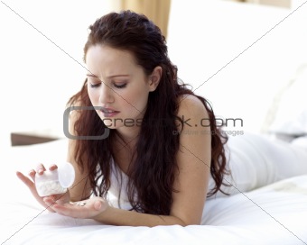 Worried woman in bed taking pills
