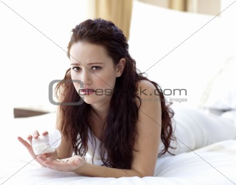 Concerned woman in bed taking pills