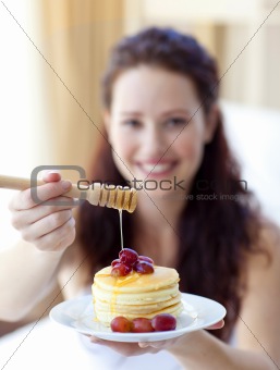 Woman holding pancakes with fruit and honey