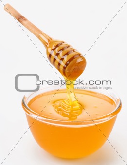 Honey pouring from stick to the bowl