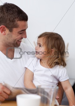 Father reading a newspaper smiling to his daughter