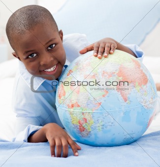 Boy looking at a globe while smiling at the camera