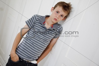 Boy leaning against the wall looking sad
