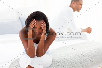 Upset Afro-american couple sitting on bed separately