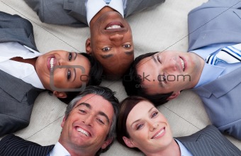 Multi-ethnic business team lying on the floor with heads togethe