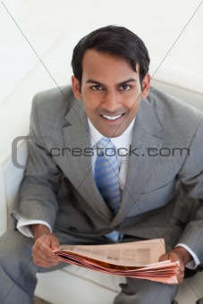 Businessman reading a newspaper and sitting in a waiting room