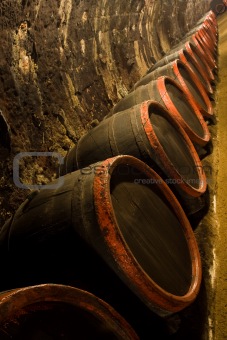 Row of Wine barrels in winery cellar recedes into the distance