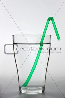 a full water glass with a green drinking straw