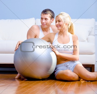 Couple Sitting on Floor With Silver Exercise Ball