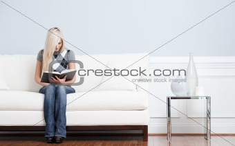 Woman Sitting on Couch and Reading Book