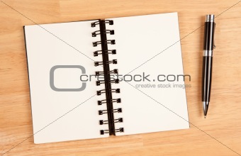 Blank Spiral Note Pad and Pen on Wood Background.