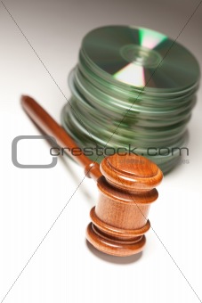 Stack of CD Rom or DVD Discs and Gavel on a Gradated Background.