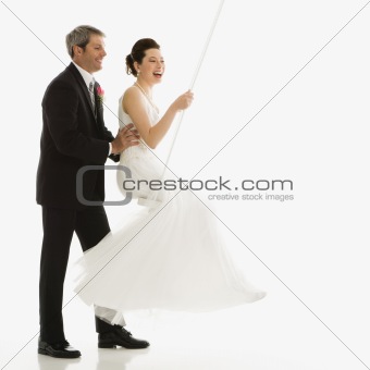 Groom pushing bride in swing.