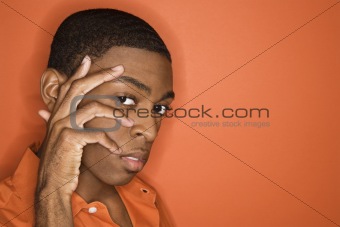 African-American man with his hand on his face.