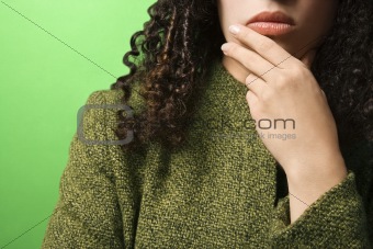 Caucasian woman with hand on chin wearing green clothing.