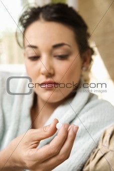 Sick woman in robe holding pill.