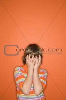 Caucasian boy with hands covering face. 