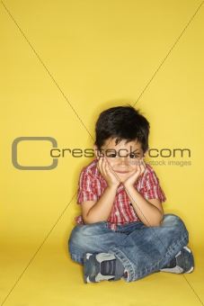 Boy sitting with head on hands.