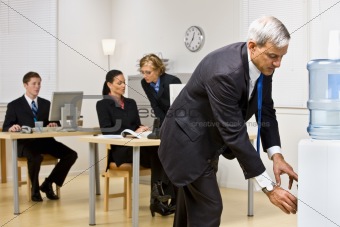 Businessman getting water from water cooler